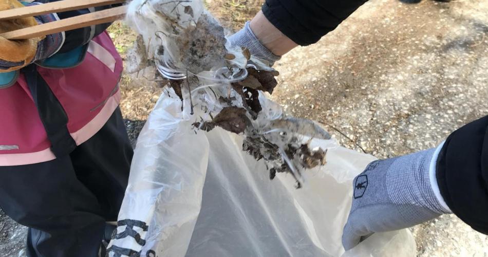 Müllsack wird von Kindern mit gefundenem Müll gefüllt