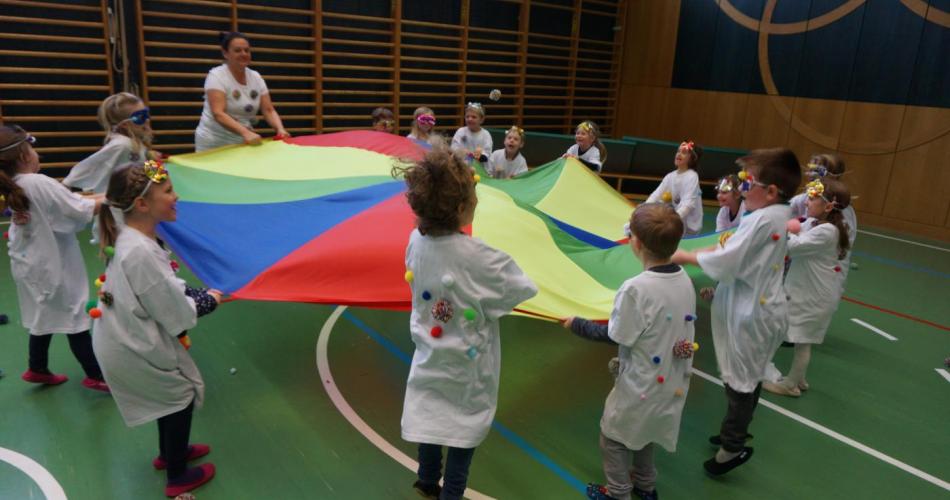 Kinder spielen mit dem Fallschirm