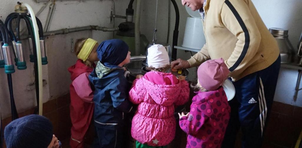 Kinder sehen sich die Milchkanne an